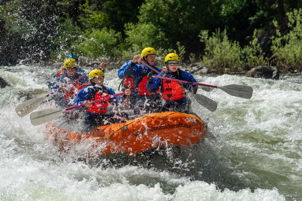 Close-up of rafters paddling through a rapid with water splashing into the boat on the Payette River.